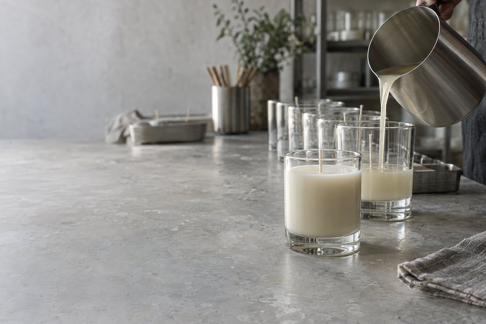 Soy wax being poured into clear glass candle vessels